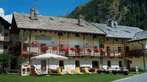 A traditional chalet with a stone roof, balconies with flower boxes, and outdoor seating. - Dresalwoald (Gressoney-Saint-Jean)