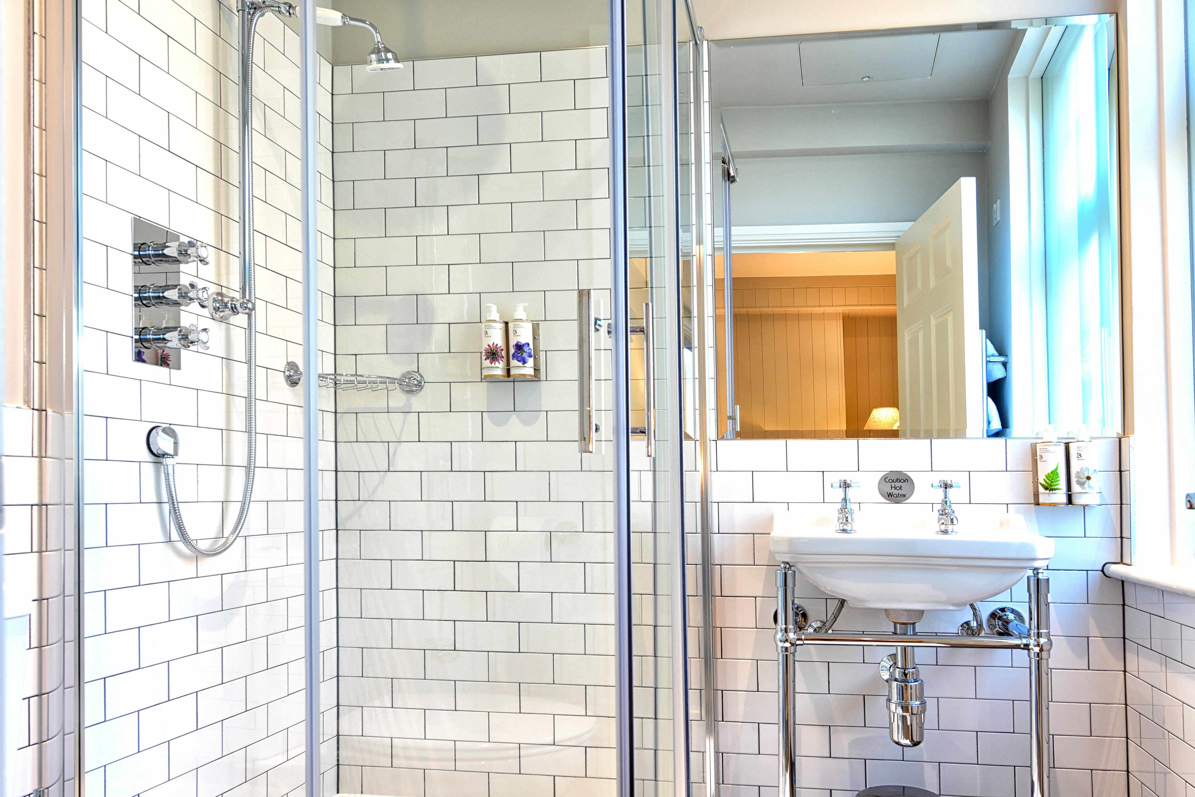 A modern bathroom with a glass-enclosed shower, a white sink with a chrome faucet, and a mirror above the sink.