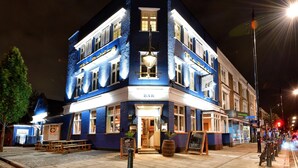 Un immeuble d’angle abritant un bar, doté de nombreuses fenêtres et donnant sur la rue.
