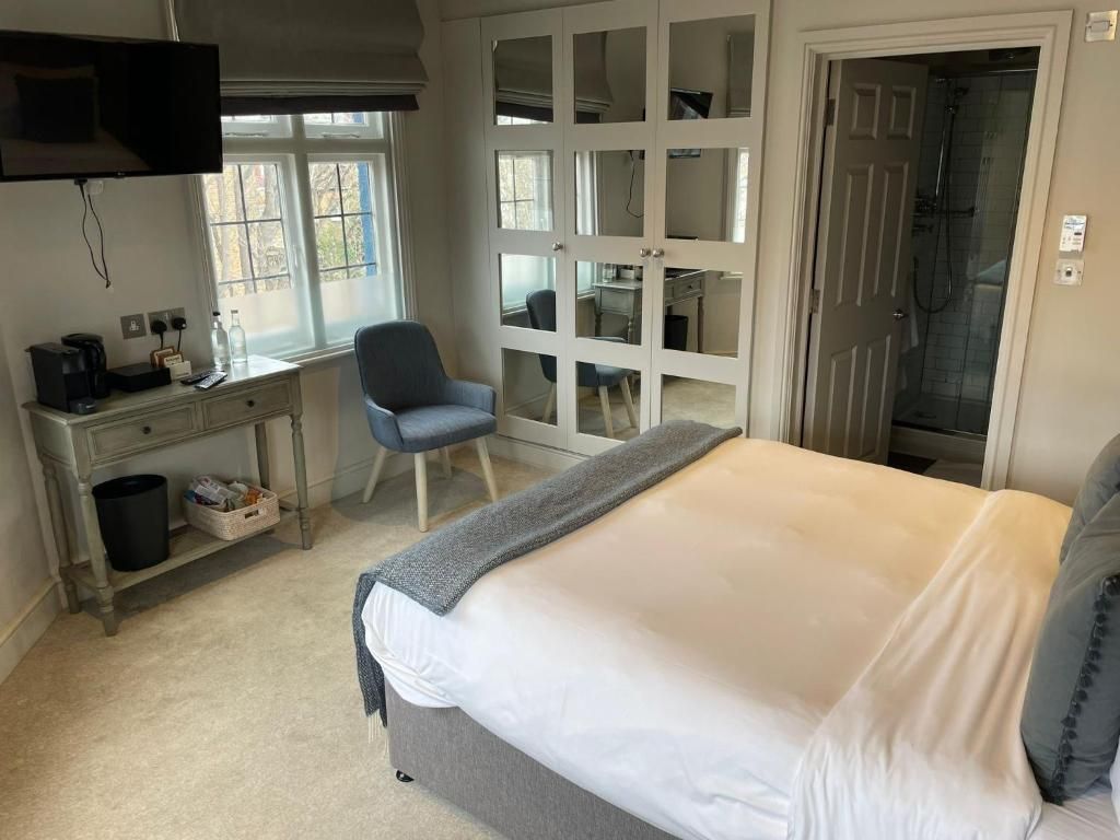 Ein Schlafzimmer mit Bett, Schreibtisch, Stuhl, Kleiderschrank und einer Dusche.