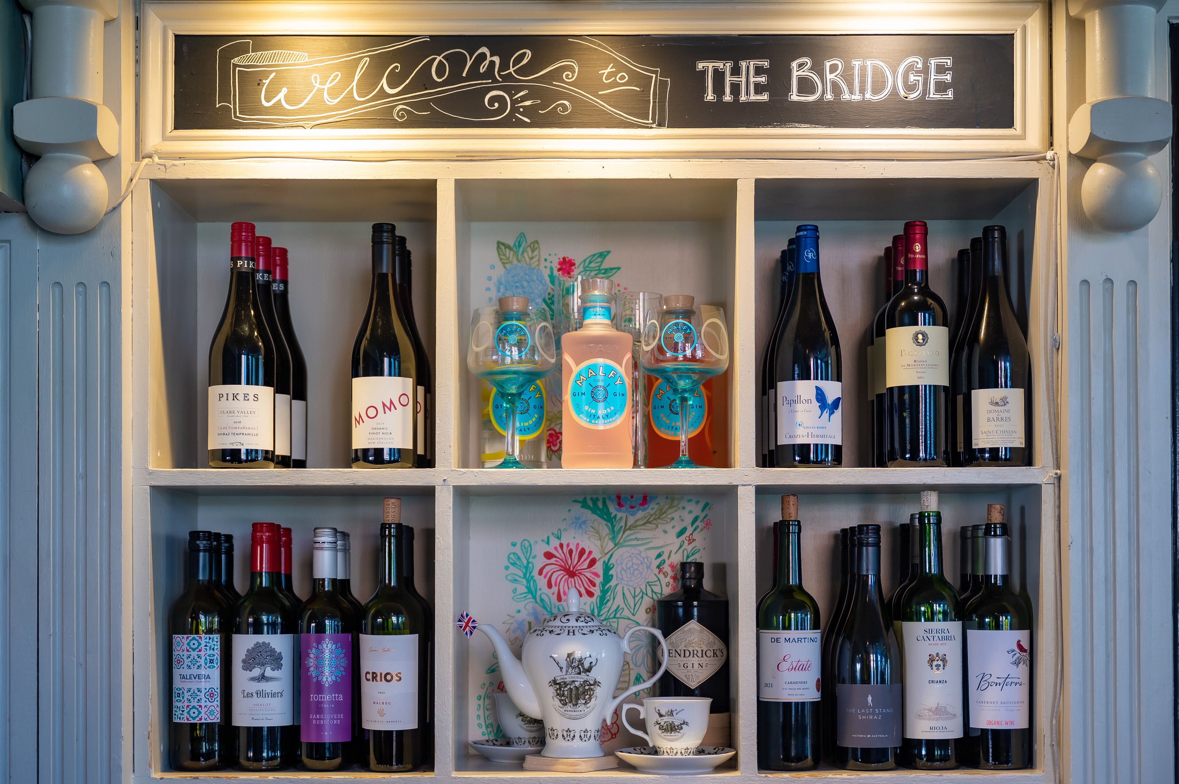A wine display with various bottles and a decorative teapot.
