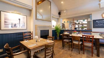 Un restaurante con muebles de madera, una chimenea y un tablero de menú en la pared.