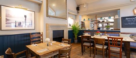 Un restaurante con muebles de madera, una chimenea y un tablero de menú en la pared.