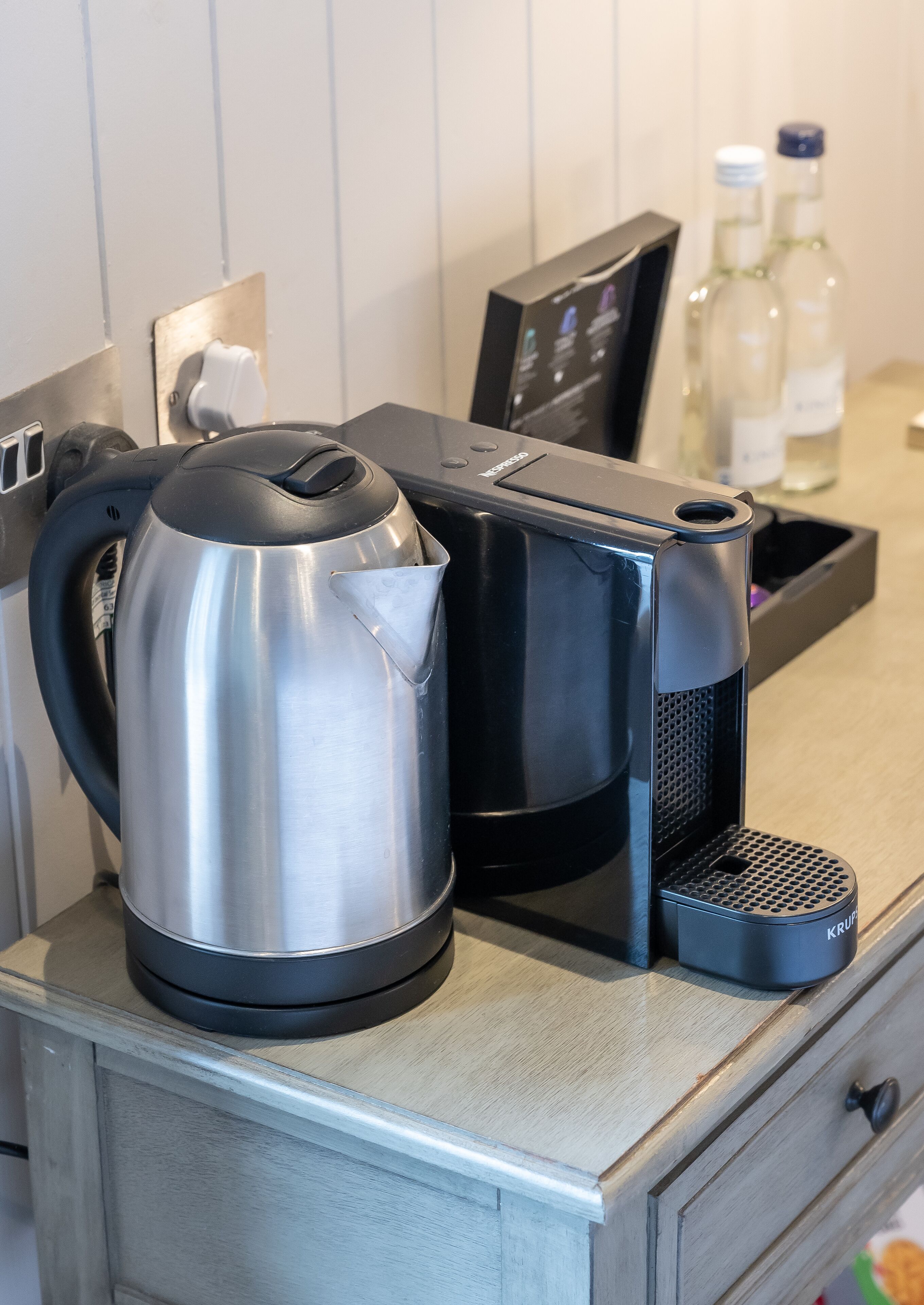 Una tetera de acero inoxidable y una cafetera sobre una encimera de madera.