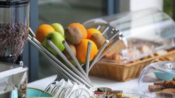 Un ricco buffet per la colazione con frutta, pane e diverse creme spalmabili.