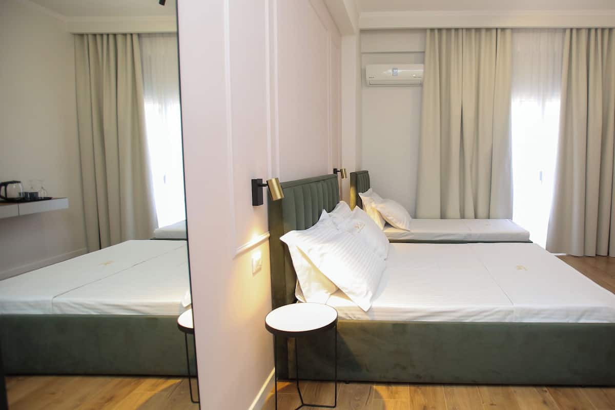 Habitación de hotel con dos camas, una mesa redonda pequeña y un espejo.