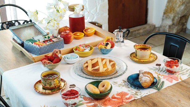 Una mesa de desayuno con diversos alimentos, como tarta, pasteles y fruta.