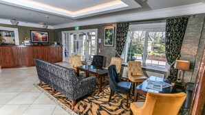 A lobby with a reception desk, seating area, and large windows. - The Ballymac Hotel (Lisburn)