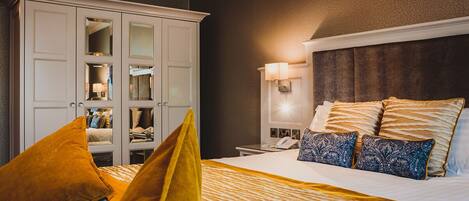 A hotel room with a large bed, a wardrobe, and a nightstand with a lamp.