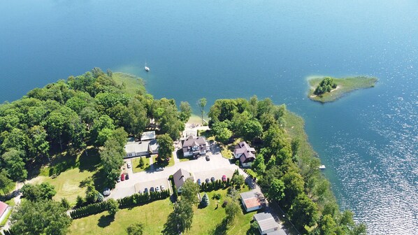 An aerial view of a lakeside property with multiple houses, a parking area, and a small island.