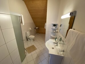 A modern bathroom with a toilet, sink, and shower.