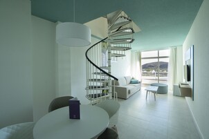Una sala de estar moderna con una escalera espiral, un comedor y vistas al exterior.