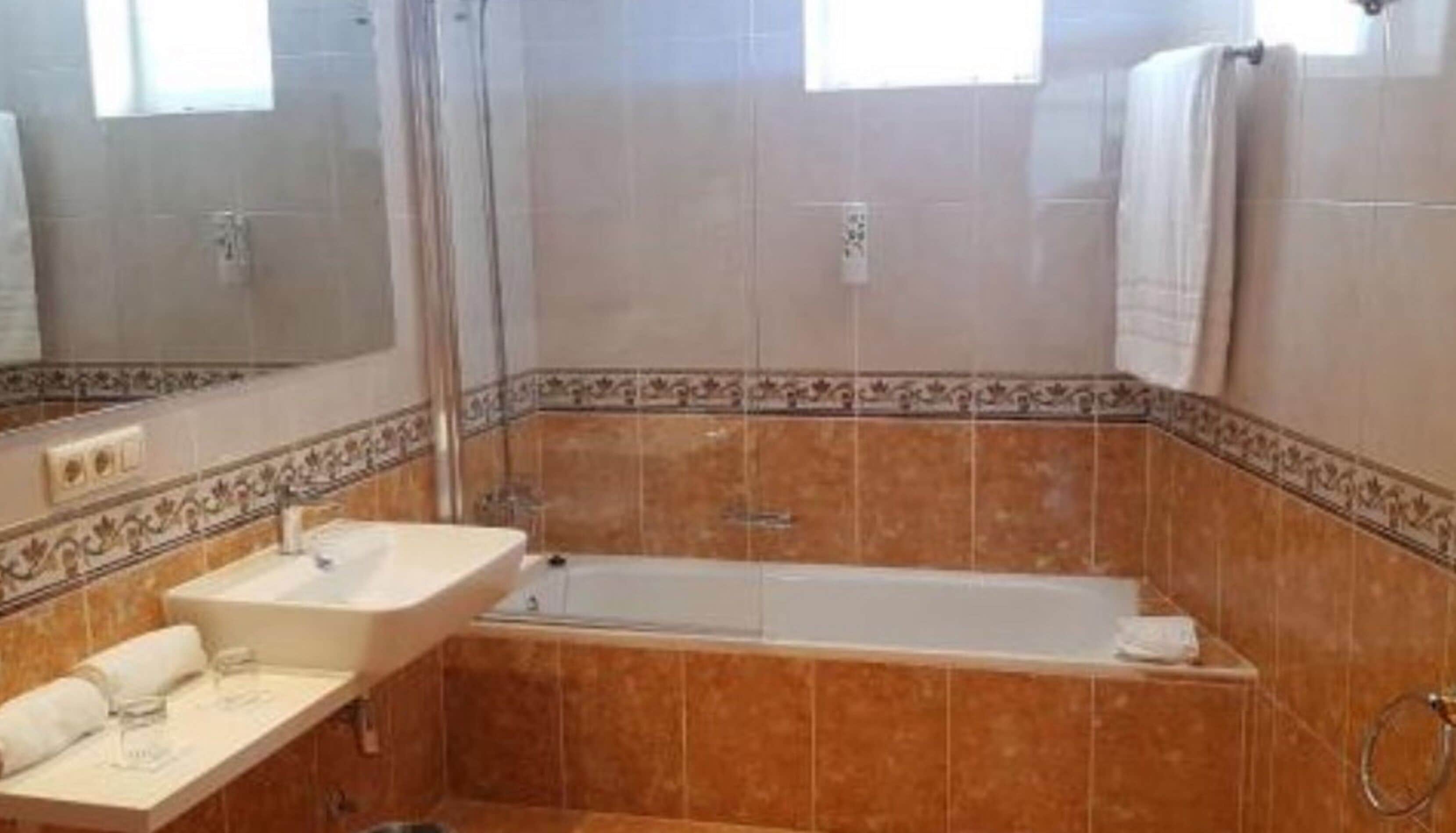 Um banheiro com banheira, pia e espelho.