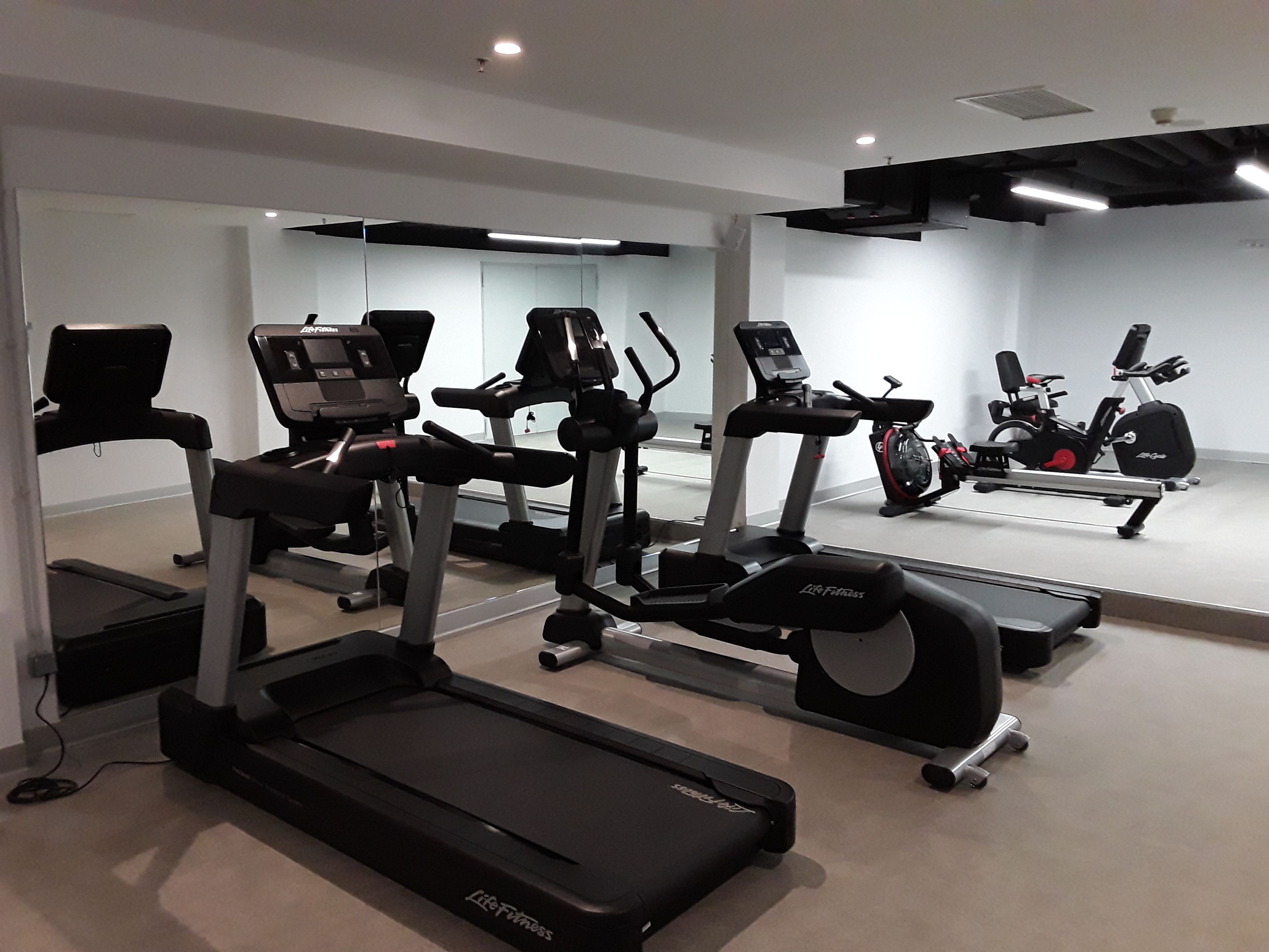 Un gimnasio con cintas de correr, bicicletas estáticas y elípticas.