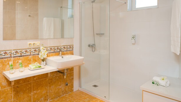 A modern bathroom with a glass-enclosed shower, a white sink, and a vanity with a mirror. - Gara Suites Golf & SPA (Arona)