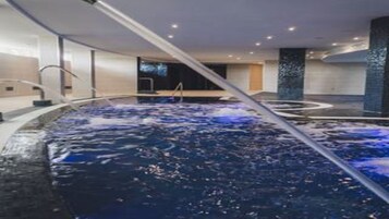 A modern indoor swimming pool with a central water feature and a sleek, contemporary design.