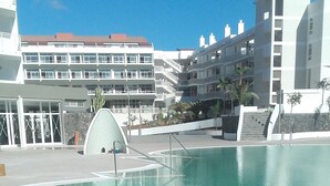 A clear blue pool with a modern design, surrounded by buildings with balconies and a clear sky. - Gara Suites Golf & SPA (Arona)