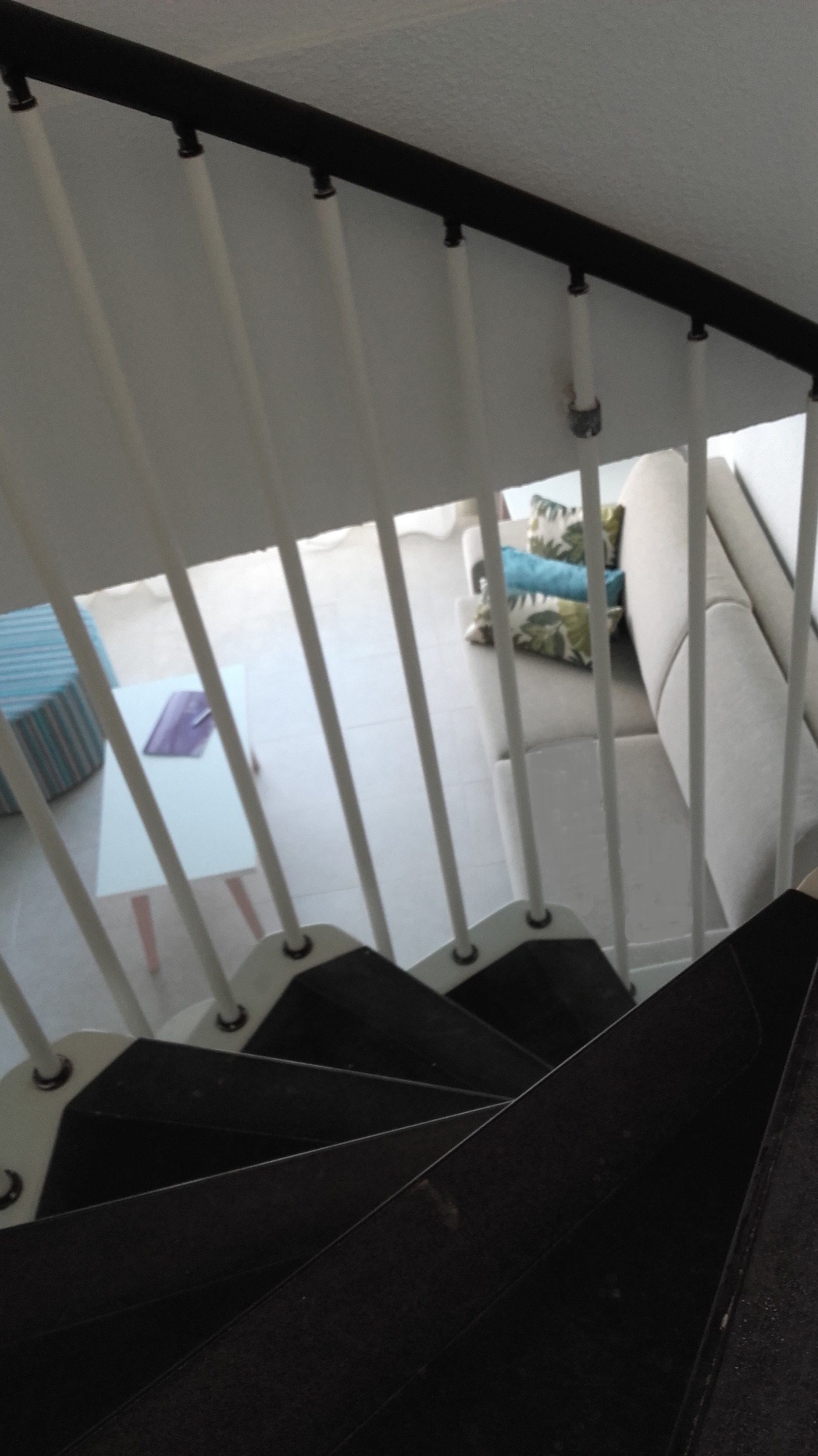A staircase with a white railing leading to a balcony.