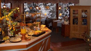 A cozy hotel bar area with a wooden counter, a Christmas tree, and a view of snow-covered trees outside. - Waldhotel Wiesemann (Waldeck)