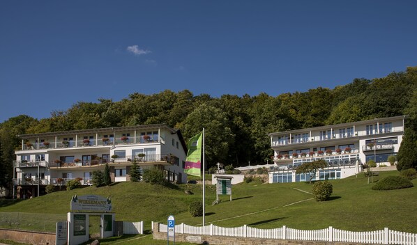 Ein Hotel mit mehreren Balkonen, einer Flagge und einem Schild, das es als Waldhotel kennzeichnet.