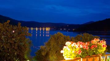 Une vue nocturne d’un lac, avec un pont et des arbres au premier plan.