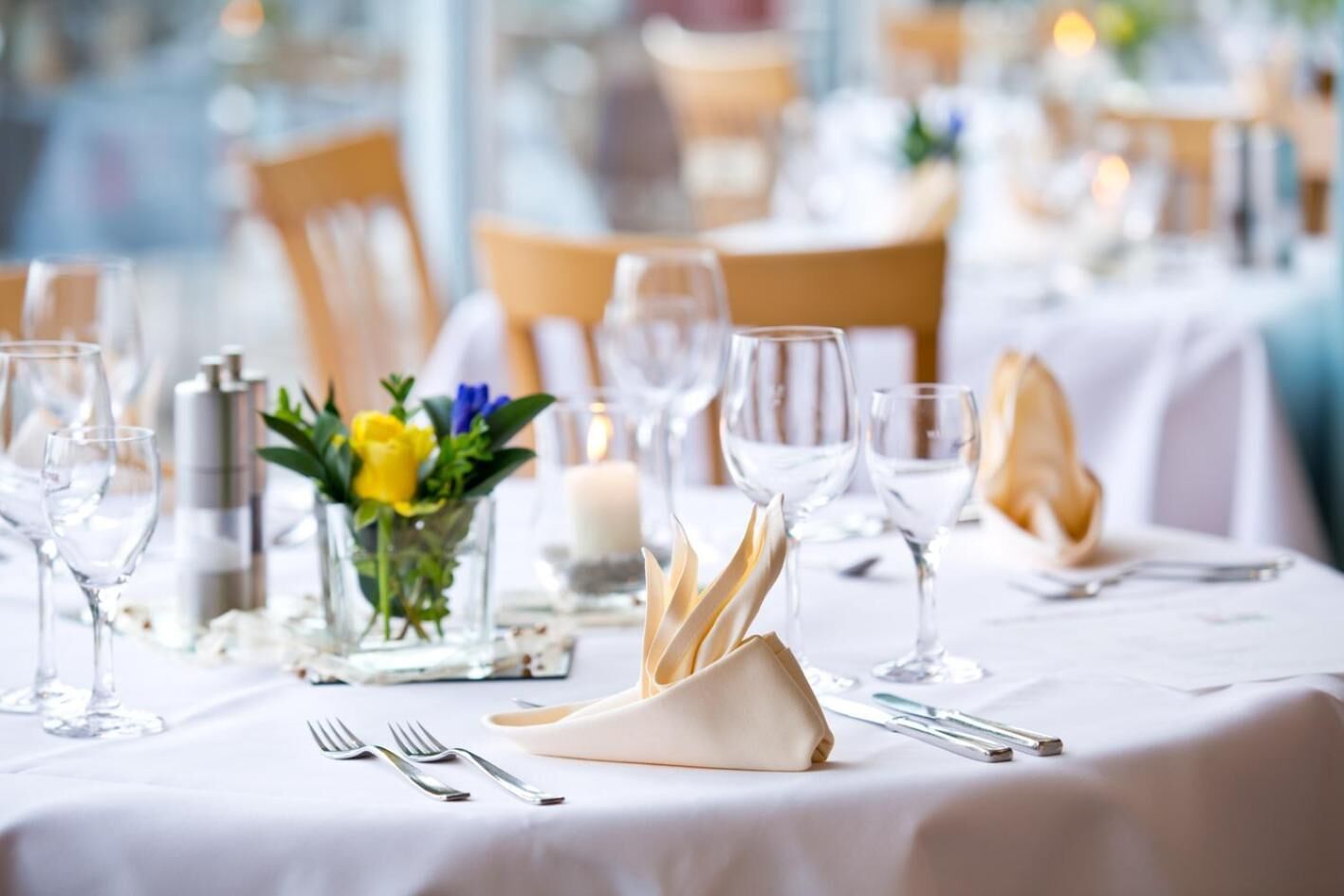 A table set for dining with clear glassware, folded napkins, and a centerpiece with flowers.
