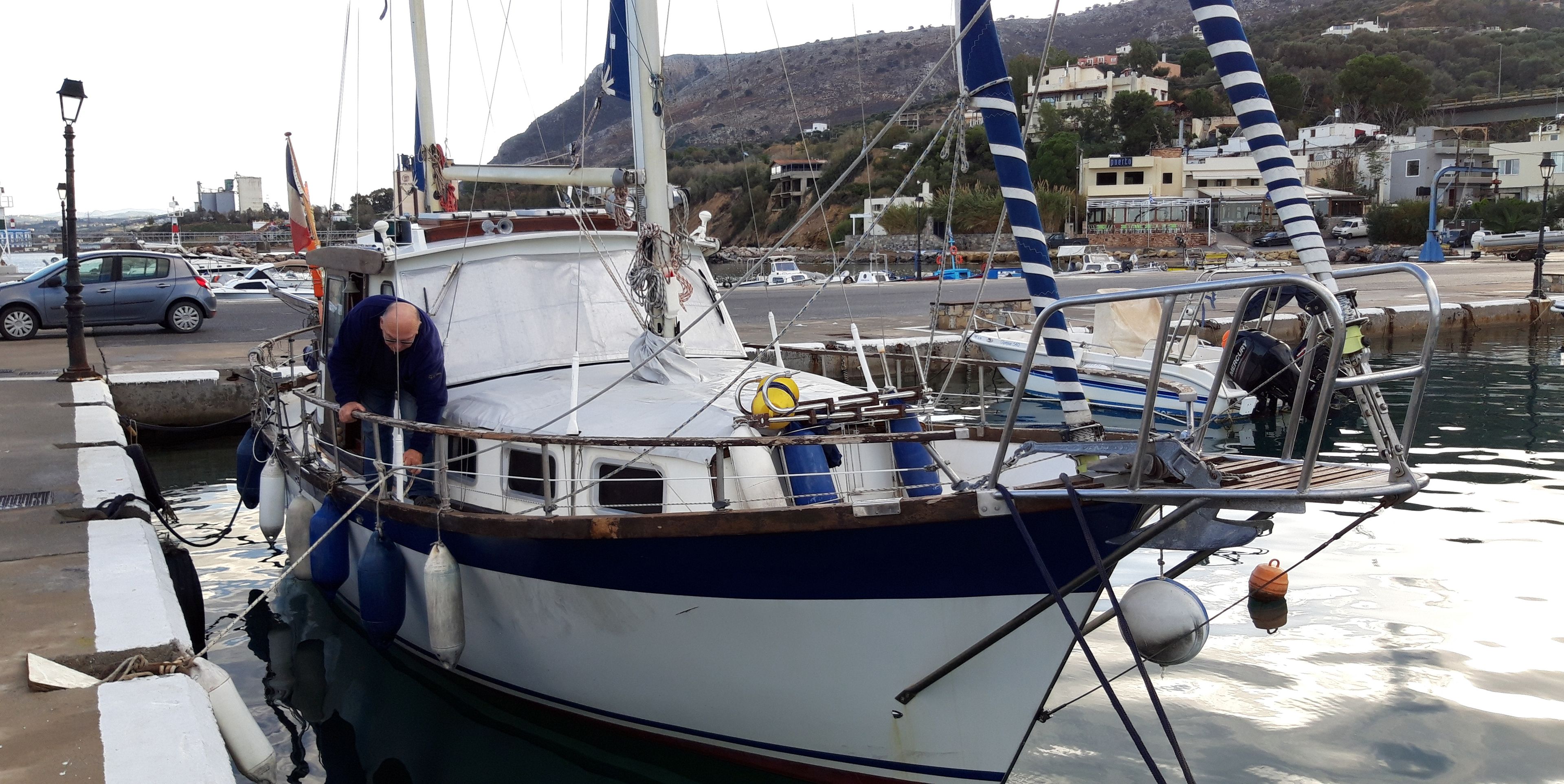A boat docked at a marina with a cityscape in the background.