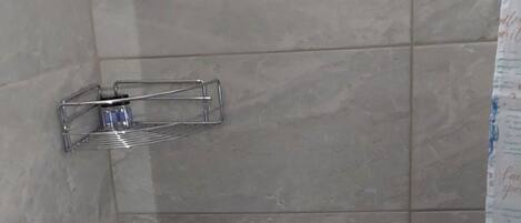 A bathroom with a toilet, a handrail, and a shower curtain.