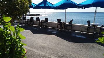 Un patio frente al mar con asientos exteriores y sombrillas.