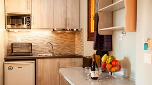 Une cuisine compacte avec des meubles en bois, un four à micro-ondes encastré, un grille-pain et un petit réfrigérateur.