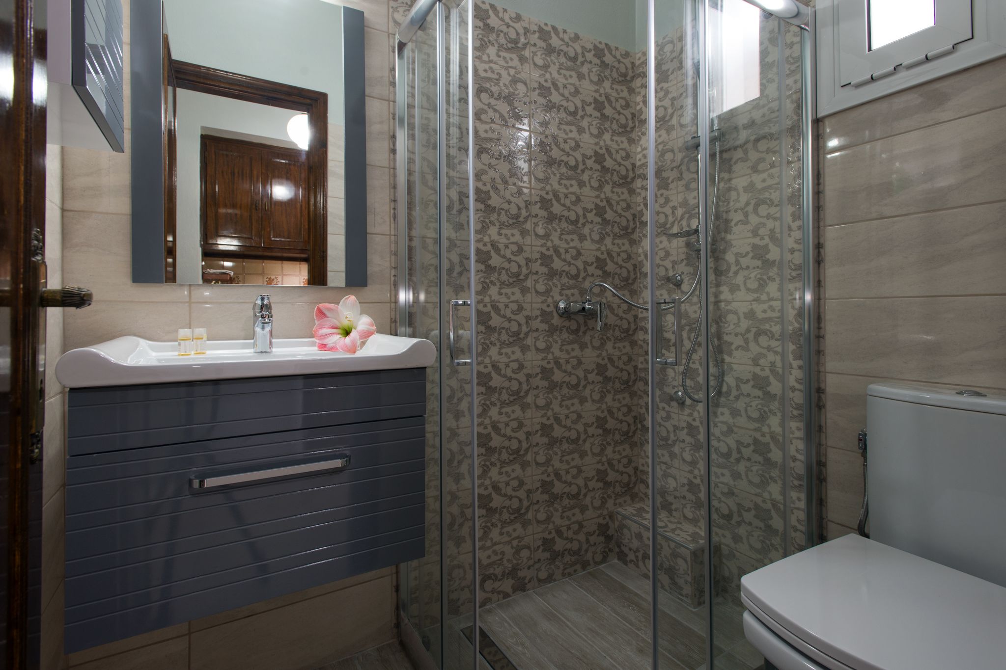 A bathroom with a shower, toilet, and vanity with a mirror.