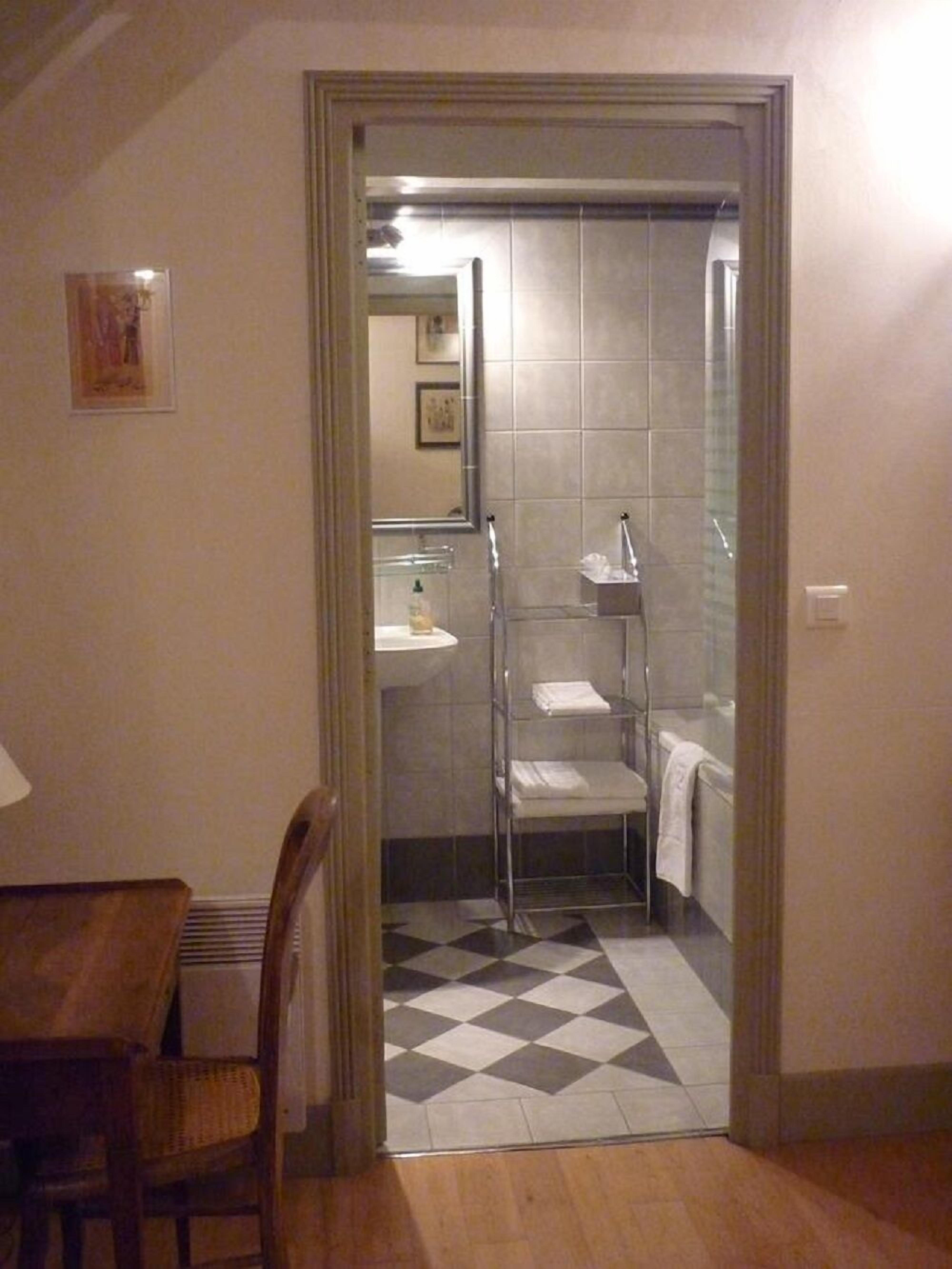 Une petite salle de bain comprenant une douche, un lavabo et une chaise.