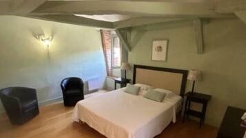 Une chambre à coucher avec un grand lit, une chaise, une table de chevet et une lampe.