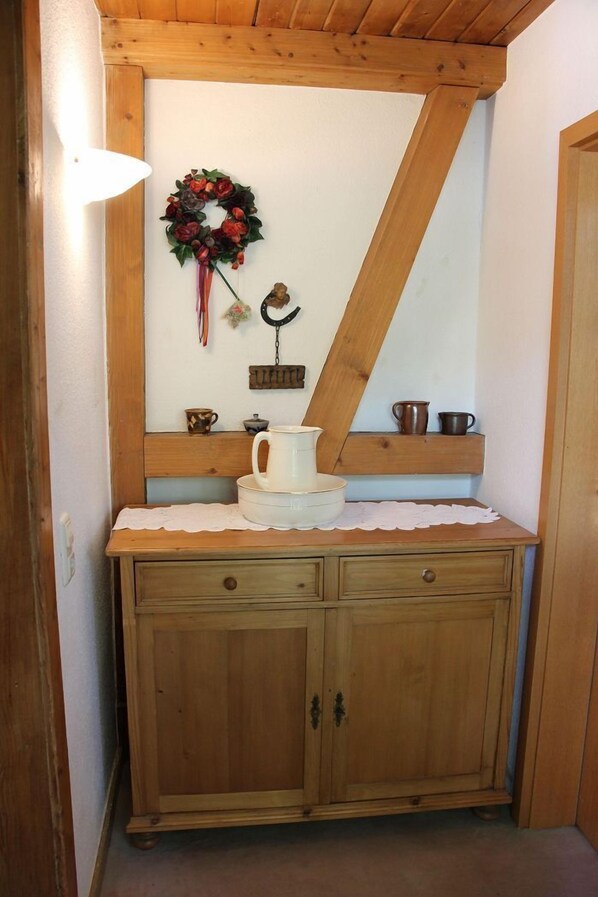 Un mueble de madera con una encimera blanca, un adorno de guirnalda y una pequeña repisa con objetos.