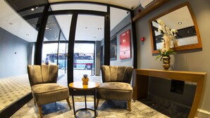 A lobby with two armchairs, a small round table, a console table with a vase, and a large mirror on the wall. - Meydan Besiktas Hotel (Istanbul)