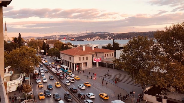 A busy urban street with a view of a body of water and hills in the distance. - Meydan Besiktas Hotel (Istanbul)