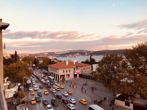 A busy urban street with a view of a body of water and hills in the distance. - Meydan Besiktas Hotel (Istanbul)