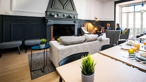A modern living room with a fireplace, seating area, and dining space. - Stay With Me Hostel (Lisbon)