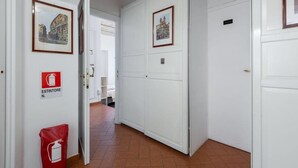 Een hal met witte deuren, ingelijste foto's en een nooduitgang.'