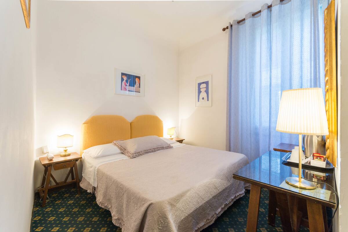 Ein Hotelzimmer mit Bett, Nachttischen, einer Lampe und einem Spiegel.