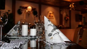 Una mesa servida con copas de vino, velas y una servilleta decorativa.