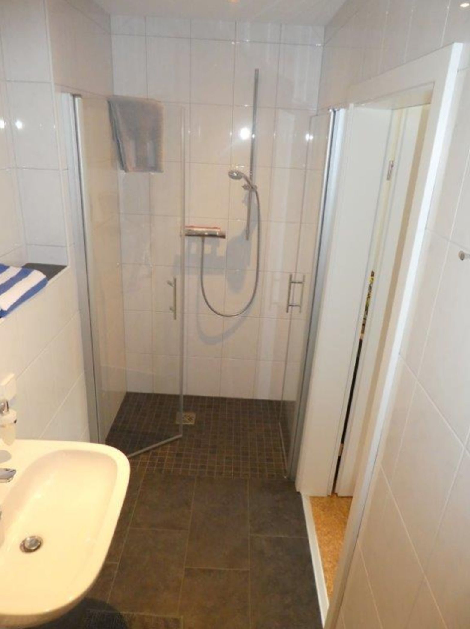 Un baño pequeño con ducha, inodoro y lavamanos.