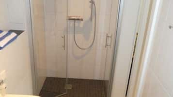 Un baño pequeño con ducha, inodoro y lavamanos.