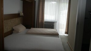 Una habitación de hotel con dos camas, un radiador y una ventana con cortinas.