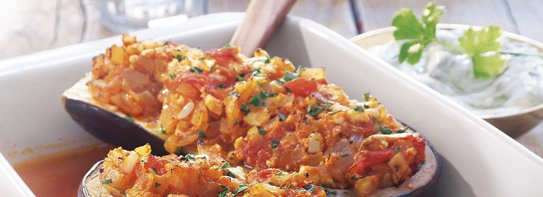 Un plato de berenjenas rellenas con salsa de tzatziki.