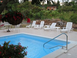 Una piscina al aire libre, sombrillas, sillones reclinables de piscina