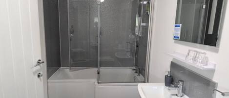 A modern bathroom with a glass-enclosed shower, a white sink, and a mirror above it.