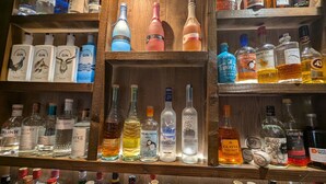 A variety of liquor bottles displayed on wooden shelves. - Old North Inn Hotel (Inverness)