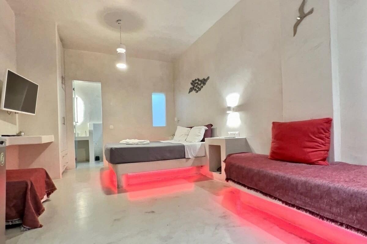 Een moderne slaapkamer met een bed, een rode bank, een bureau en een televisie.