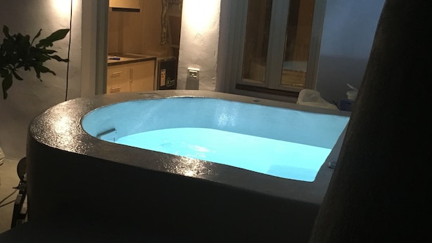 Une piscine à bord incurvé, entourée d’une terrasse aux couleurs sombres.